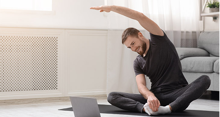Hombre haciendo ejercicio en su casa viendo su computador