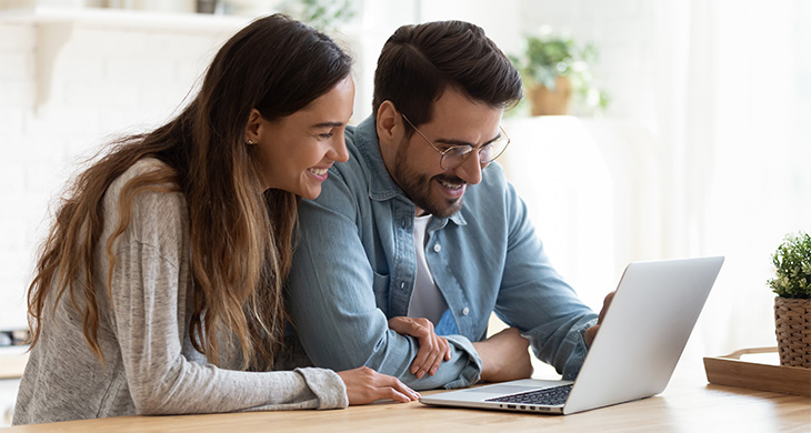 Pareja sonriente mirando un computaor