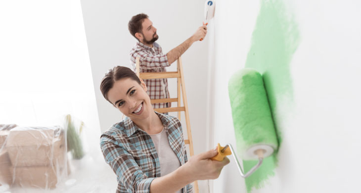 Dos personas felices pintando una habitación